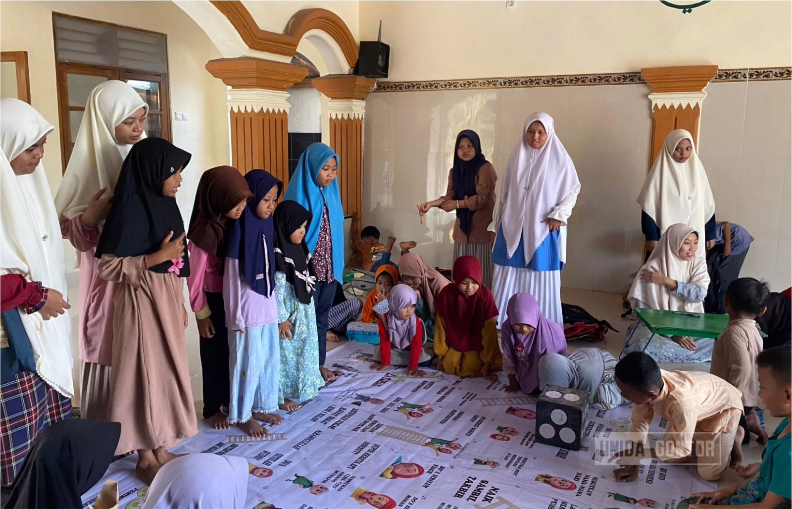 Mahasiswa Pascasarjana PBA UNIDA Gontor mengajar siswa TPA An-Nur Dadung Ngawi dengan media permainan Ular Tangga Islami untuk meningkatkan minat belajar Agama Islam.