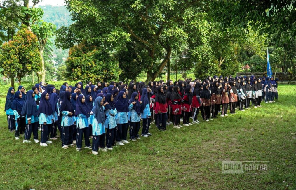 Peserta Latihan Dasar Kepemimpinan 2024 Universitas Darussalam Gontor Kelas C sedang mengikuti permainan outbound dalam suasana penuh semangat, dengan aktivitas seperti senam pagi, permainan kelompok, dan river tubing.