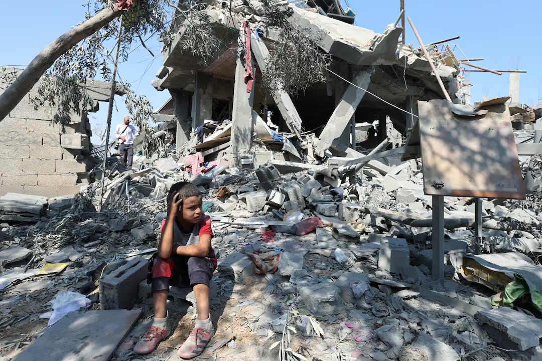 Anak Palestina duduk di antara reruntuhan bangunan di Gaza pasca serangan Israel, simbol krisis kemanusiaan yang mendalam.
