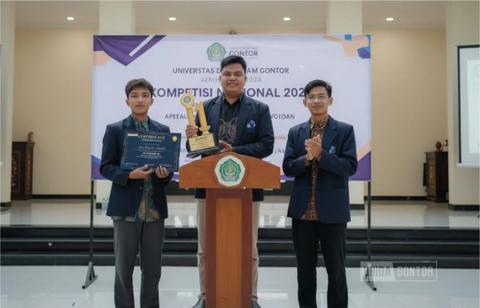 Tim Mahasiswa Ekonomi Islam UNIDA Gontor meraih Juara 1 pada Economics Research Paper FEB UPN “Veteran” Jakarta; tiga mahasiswa memegang trofi/sertifikat di panggung acara.