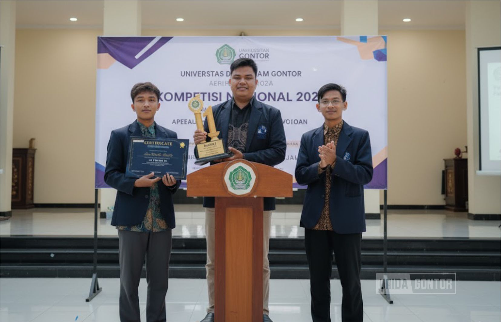 Tim Mahasiswa Ekonomi Islam UNIDA Gontor meraih Juara 1 pada Economics Research Paper FEB UPN “Veteran” Jakarta; tiga mahasiswa memegang trofi/sertifikat di panggung acara.