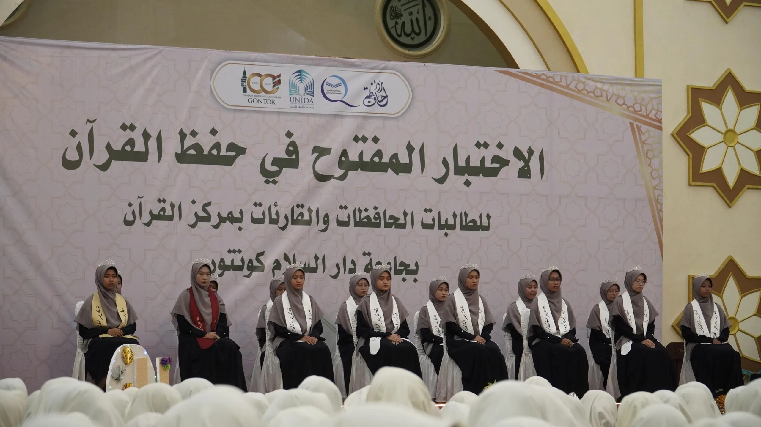 Mahasiswi memperdengarkan hafalan pada Ujian Tahfidz Terbuka 2025 di UNIDA Gontor, disimak ustadzah penguji dalam suasana khidmat.
