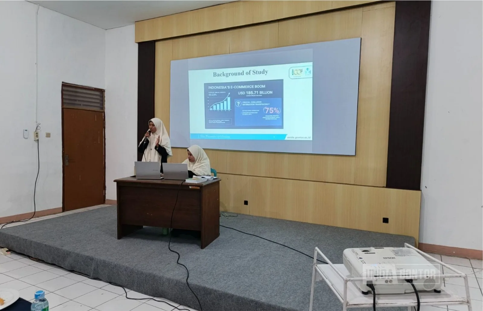 Sidang Skripsi Perdana Fakultas Syariah UNIDA Gontor di Aula CIOS Beirut Kampus Gontor Putri 1, mahasiswi HES mempresentasikan penelitian di hadapan dosen penguji.