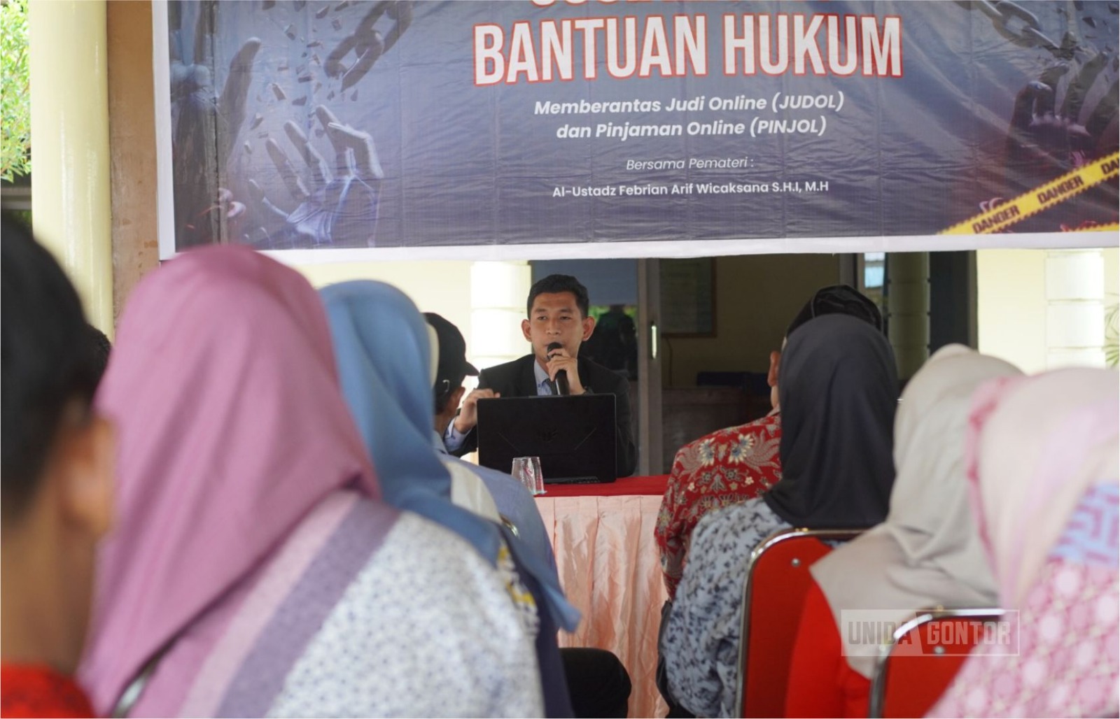 Mahasiswa KKN Tematik 38 UNIDA Gontor memberikan sosialisasi hukum bahaya judol dan pinjol kepada warga Desa Nailan di Balai Desa.