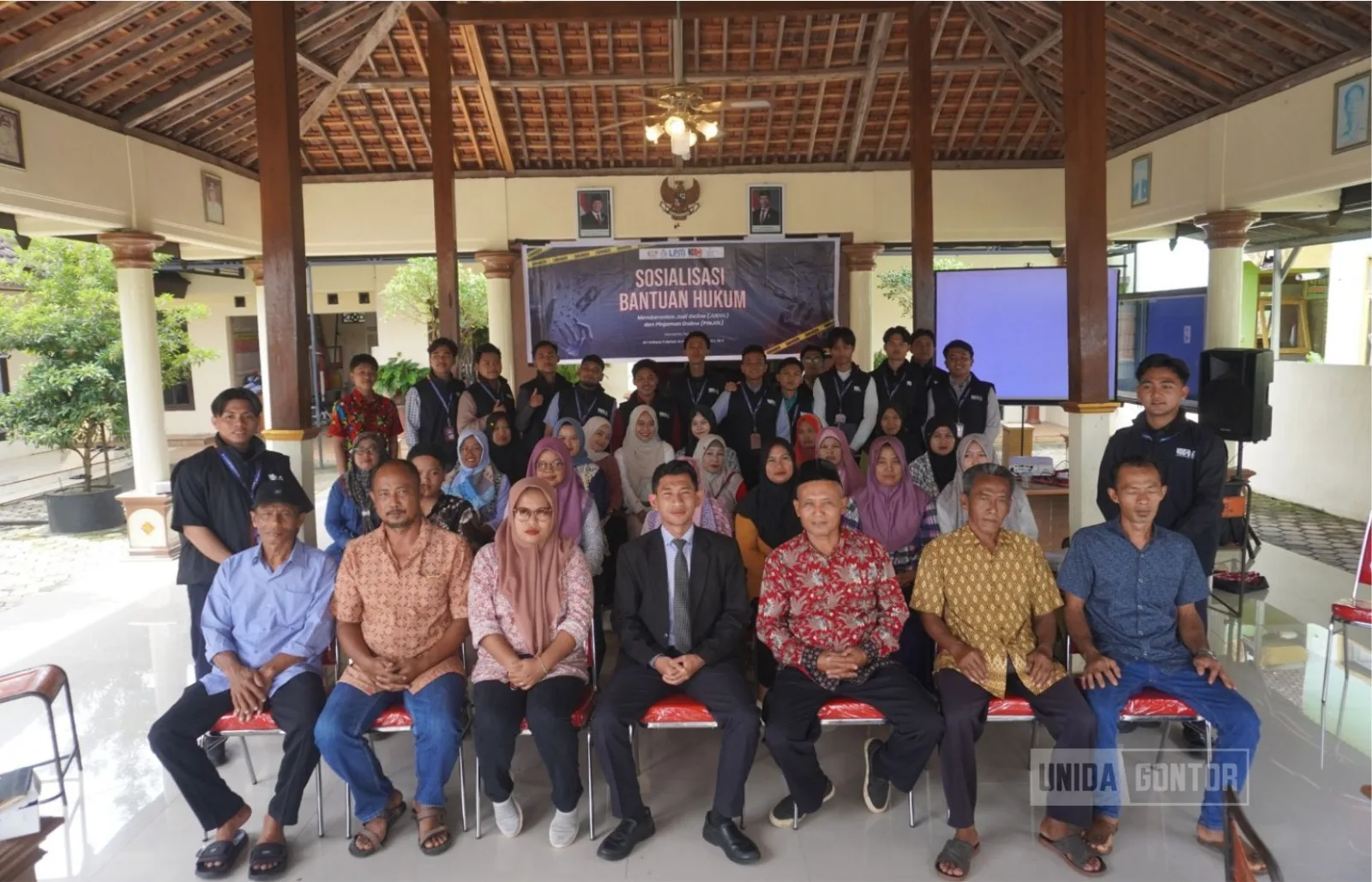 Mahasiswa KKN Tematik 38 UNIDA Gontor memberikan sosialisasi hukum bahaya judol dan pinjol kepada warga Desa Nailan di Balai Desa.